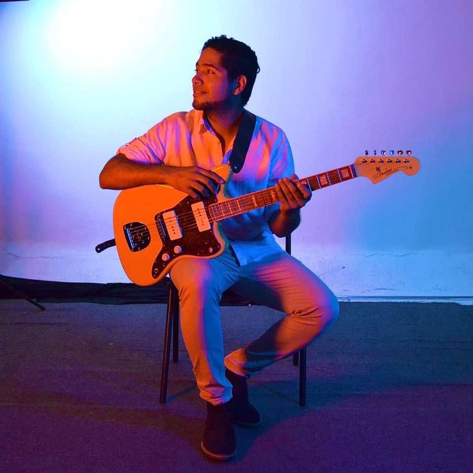 Gilberth Roca tocando guitarra eléctrica bajo luces de escenario